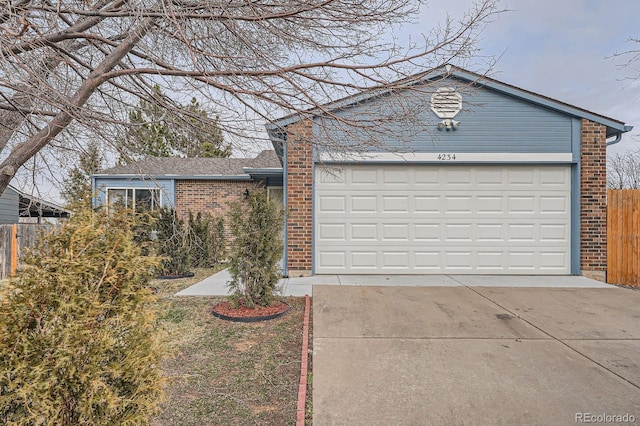 single story home with concrete driveway, brick siding, an attached garage, and fence