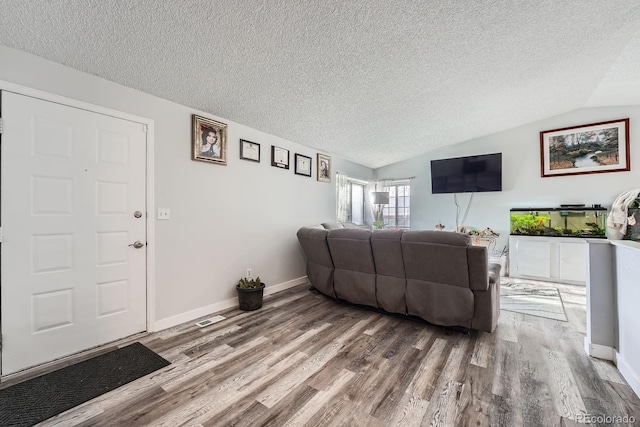 living room with vaulted ceiling, a textured ceiling, and wood finished floors