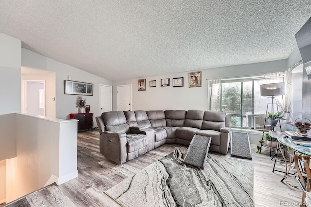 living area featuring vaulted ceiling, a textured ceiling, and light wood-style floors