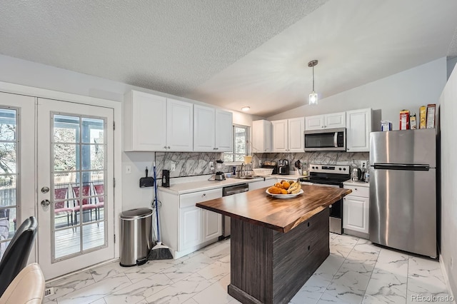 kitchen with marble finish floor, stainless steel appliances, a sink, and wooden counters