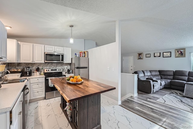 kitchen with open floor plan, marble finish floor, stainless steel appliances, wooden counters, and a sink