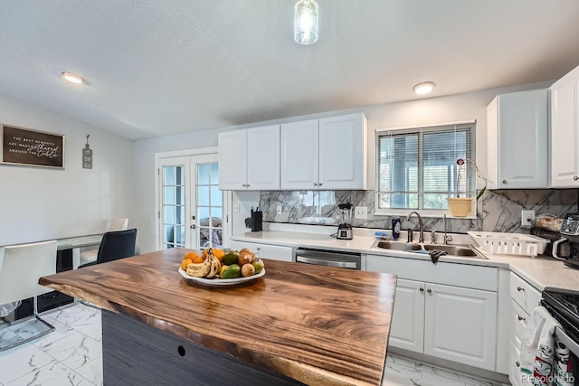 kitchen featuring marble finish floor, lofted ceiling, backsplash, stainless steel dishwasher, and a sink