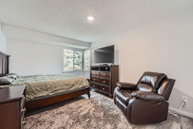 bedroom featuring a textured ceiling, wood finished floors, and baseboards