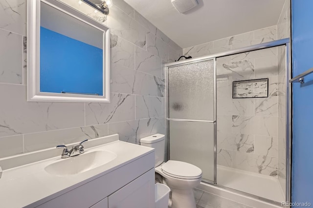 full bath with a stall shower, visible vents, toilet, vanity, and tile walls