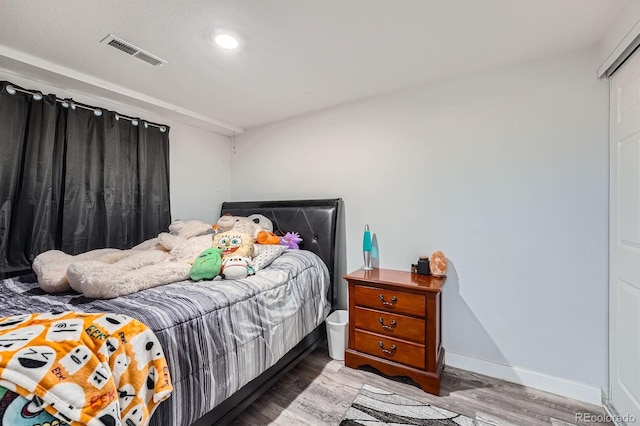 bedroom with visible vents, baseboards, and wood finished floors