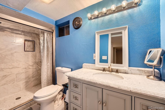 full bathroom featuring a stall shower, a textured wall, toilet, a textured ceiling, and vanity