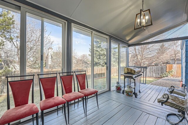 sunroom with a wealth of natural light, a notable chandelier, and vaulted ceiling