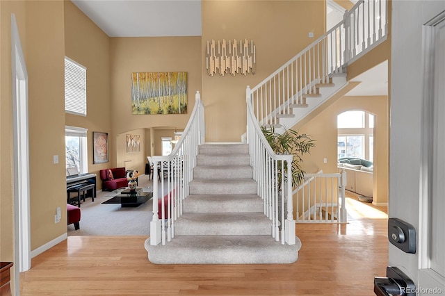 staircase featuring wood-type flooring and a high ceiling