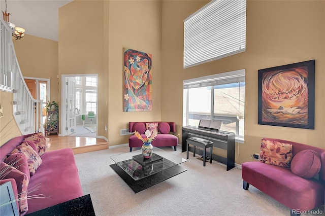 living room with light carpet, a towering ceiling, and a healthy amount of sunlight