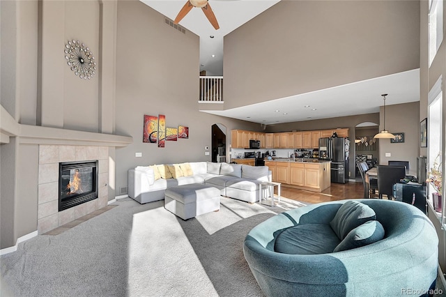 carpeted living room with ceiling fan and a fireplace