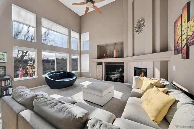 living room featuring a fireplace, carpet floors, a high ceiling, and ceiling fan