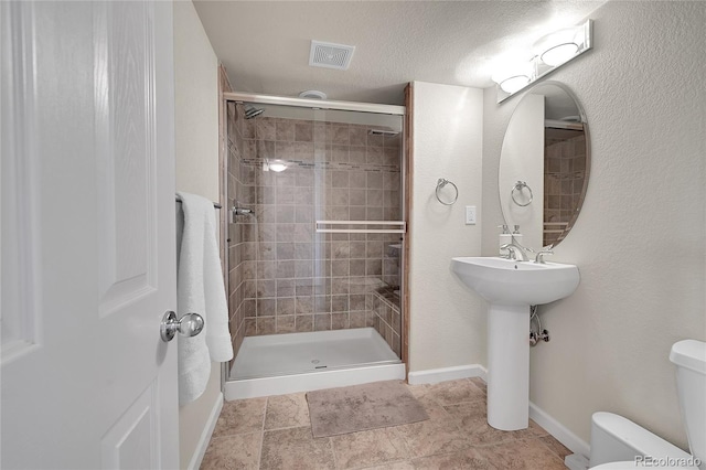 bathroom featuring tile patterned flooring, toilet, a shower with shower door, a textured ceiling, and sink