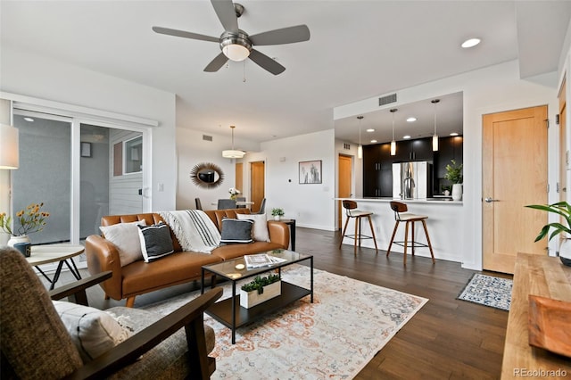 living room featuring dark wood-type flooring, ceiling fan, visible vents, and recessed lighting