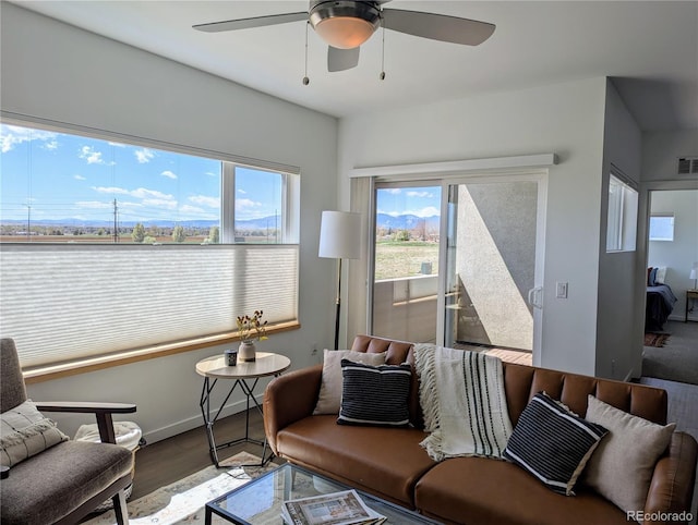 living room with baseboards, a ceiling fan, wood finished floors, and visible vents