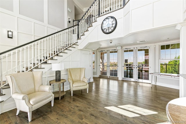 interior space featuring french doors, a towering ceiling, a healthy amount of sunlight, and hardwood / wood-style floors