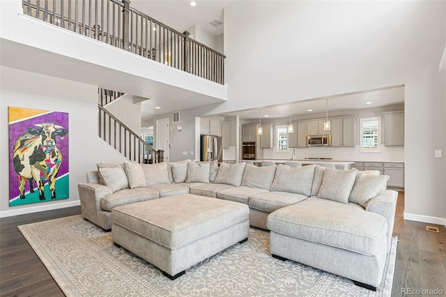 living room with sink, a towering ceiling, and light wood-type flooring