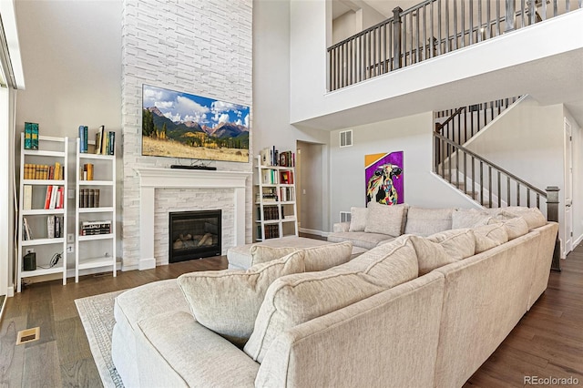 living room featuring dark hardwood / wood-style floors, a towering ceiling, and a fireplace