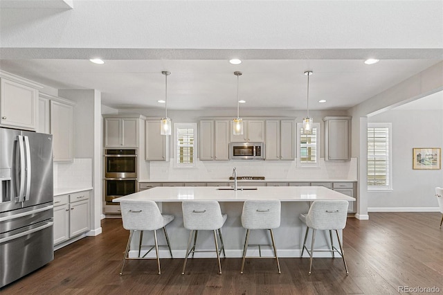 kitchen with pendant lighting, plenty of natural light, stainless steel appliances, and an island with sink