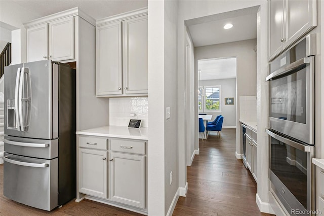 kitchen with white cabinets, dark hardwood / wood-style floors, decorative backsplash, and stainless steel appliances