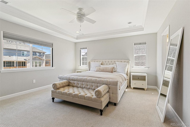 carpeted bedroom featuring a tray ceiling, multiple windows, ceiling fan, and ornamental molding