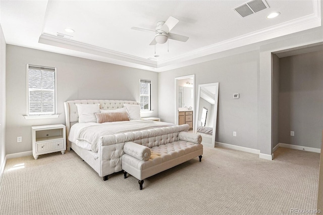 bedroom featuring light carpet, a raised ceiling, crown molding, ensuite bath, and ceiling fan