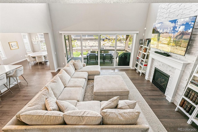 living room with a stone fireplace, a high ceiling, and dark hardwood / wood-style floors