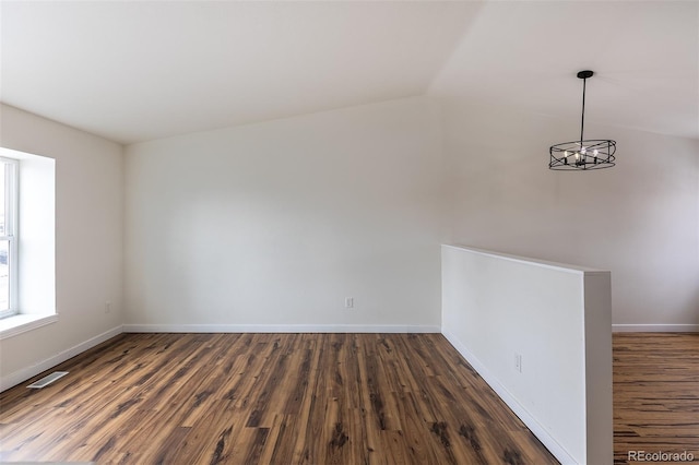 unfurnished room with lofted ceiling, baseboards, visible vents, and wood finished floors