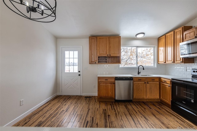 kitchen with stainless steel appliances, dark wood-style flooring, a sink, and tasteful backsplash