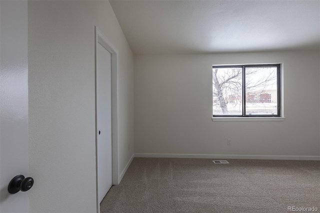 carpeted empty room featuring baseboards and visible vents