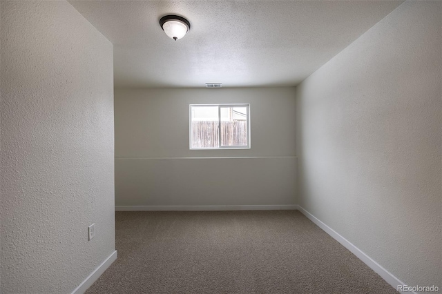 carpeted spare room with visible vents, baseboards, a textured ceiling, and a textured wall