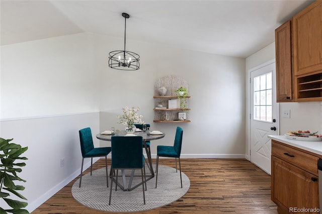 dining area featuring dark wood-style floors, vaulted ceiling, a chandelier, and baseboards