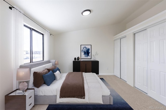 bedroom featuring carpet and two closets