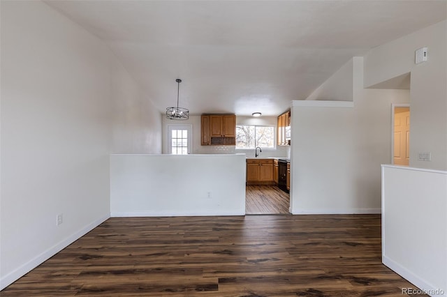 kitchen featuring baseboards, dark wood-style floors, brown cabinets, a peninsula, and light countertops