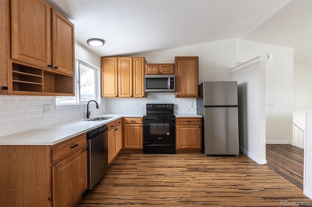 kitchen featuring stainless steel appliances, dark wood-style flooring, a sink, vaulted ceiling, and light countertops