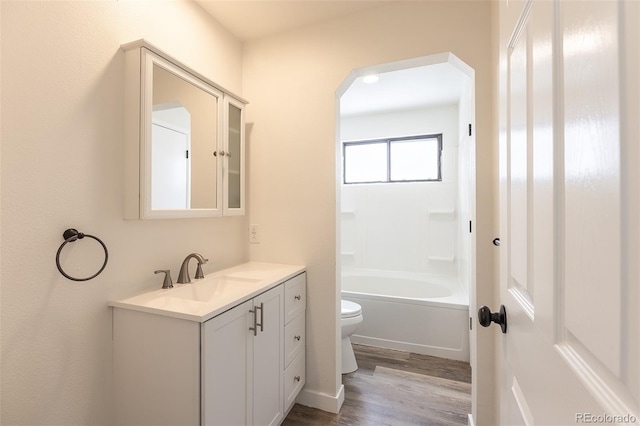 bathroom with toilet, tub / shower combination, wood finished floors, and vanity