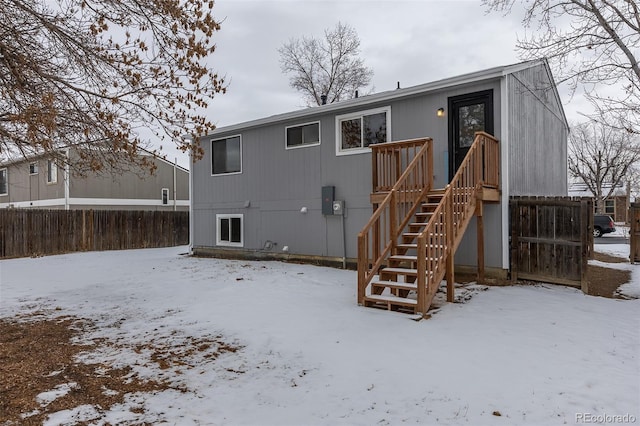 snow covered house with stairs and fence