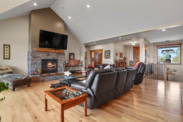 living area with recessed lighting, light wood-style flooring, high vaulted ceiling, and a stone fireplace