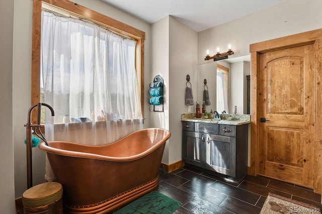 bathroom with a freestanding tub, vanity, and baseboards