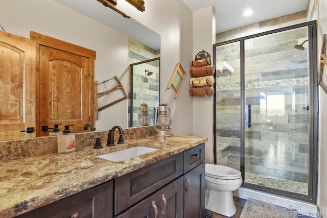 bathroom with toilet, a stall shower, and vanity