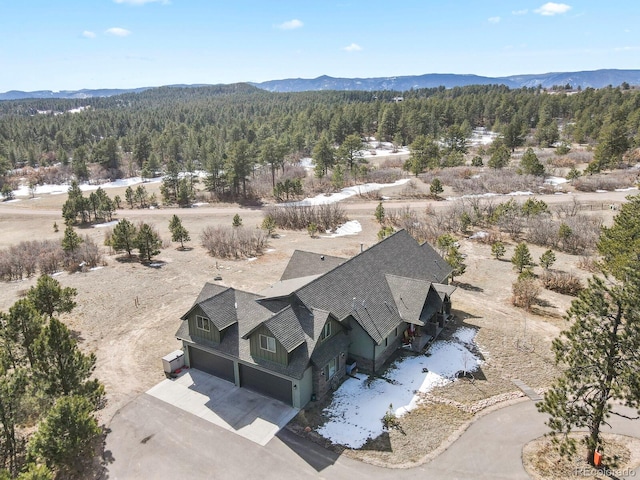 drone / aerial view with a wooded view and a mountain view