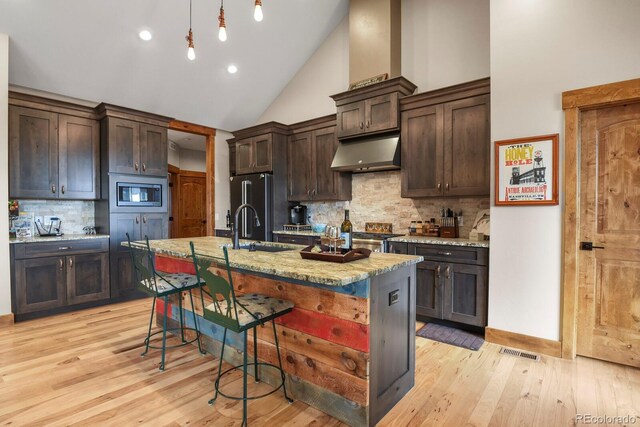 5800 Elk View Ct, Larkspur, CO 80118 - kitchen featuring under cabinet range hood, a sink, stainless steel microwave, high vaulted ceiling, and backsplash