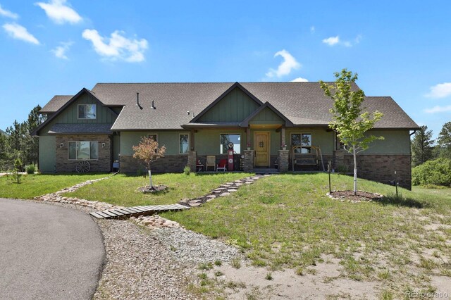 5800 Elk View Ct, Larkspur, CO 80118 - craftsman house featuring a front lawn, brick siding, a shingled roof, and covered porch