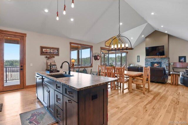5800 Elk View Ct, Larkspur, CO 80118 - kitchen featuring a sink, open floor plan, light wood-style flooring, a fireplace, and a kitchen island with sink