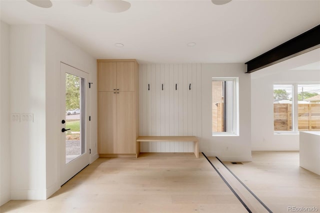 empty room with beam ceiling and light wood-style flooring