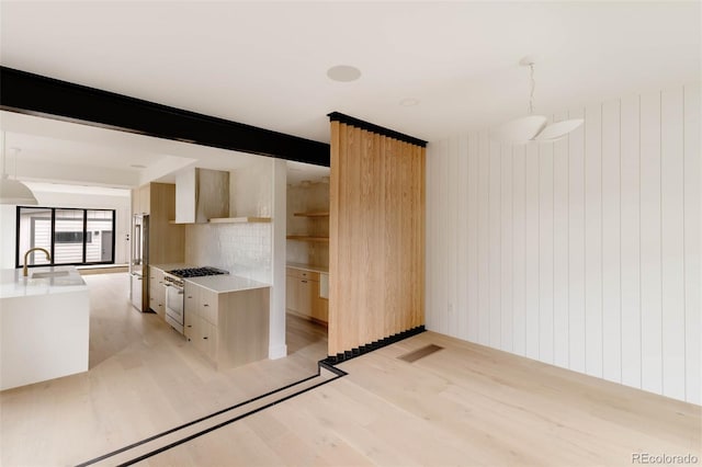 kitchen with light wood finished floors, high quality fridge, a sink, white gas range oven, and modern cabinets