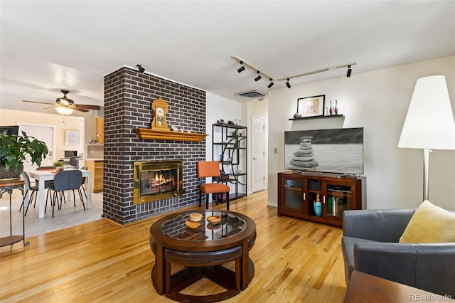 9598 Lowell Blvd, Westminster, CO 80031 - living area featuring a brick fireplace, wood finished floors, ceiling fan, and track lighting
