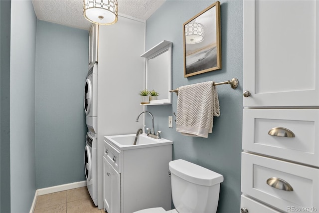 909 N Logan St Unit 1B, Denver, CO 80203 - half bath with stacked washing machine and dryer, vanity, a textured ceiling, and tile patterned flooring