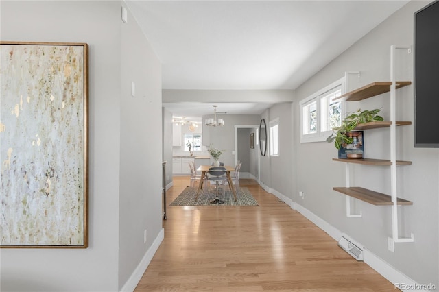 4933 Grove St, Denver, CO 80221 - hallway with light wood-style flooring, plenty of natural light, a chandelier, and baseboards