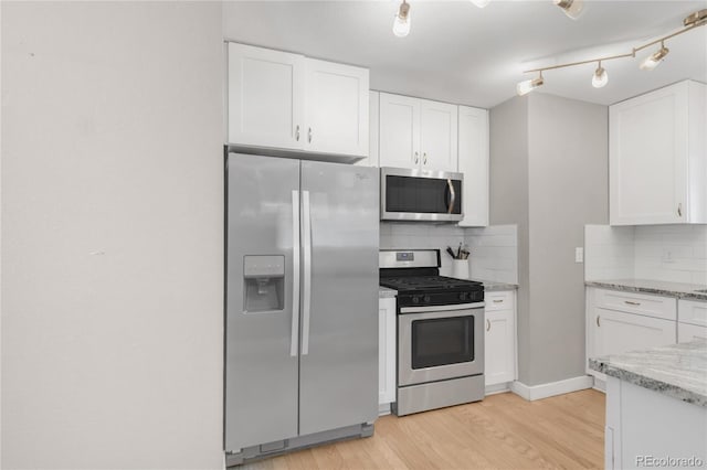 4933 Grove St, Denver, CO 80221 - kitchen featuring stainless steel appliances, white cabinets, decorative backsplash, and light wood finished floors