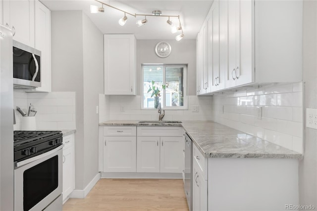 4933 Grove St, Denver, CO 80221 - kitchen with stainless steel appliances, a sink, white cabinetry, light wood-style flooring, and tasteful backsplash